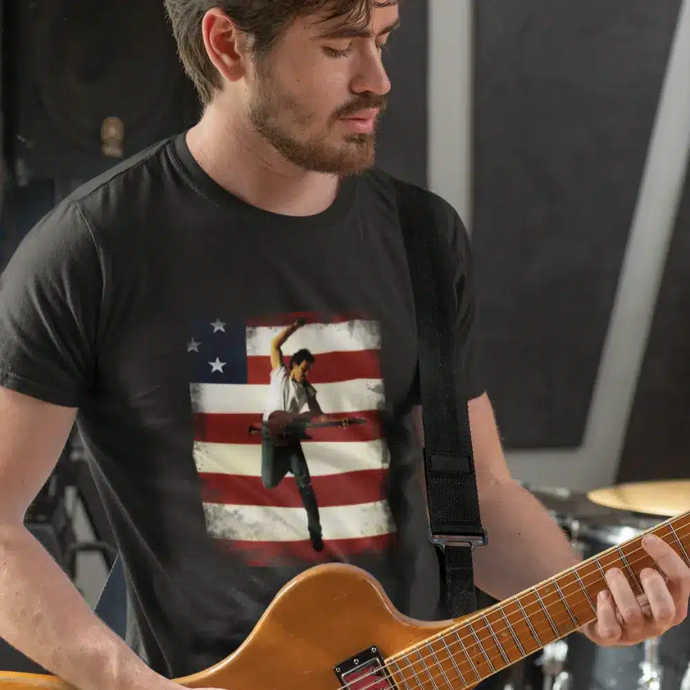 Man playing guitar while wearing a dark gray t-shirt featuring an image of Bruce Springsteen in front of an American flag.