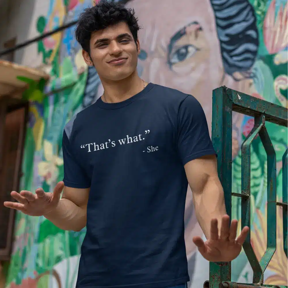 Man wearing a navy blue t-shirt with 'That's what. - She' design from the OTL Spotlight curated collection