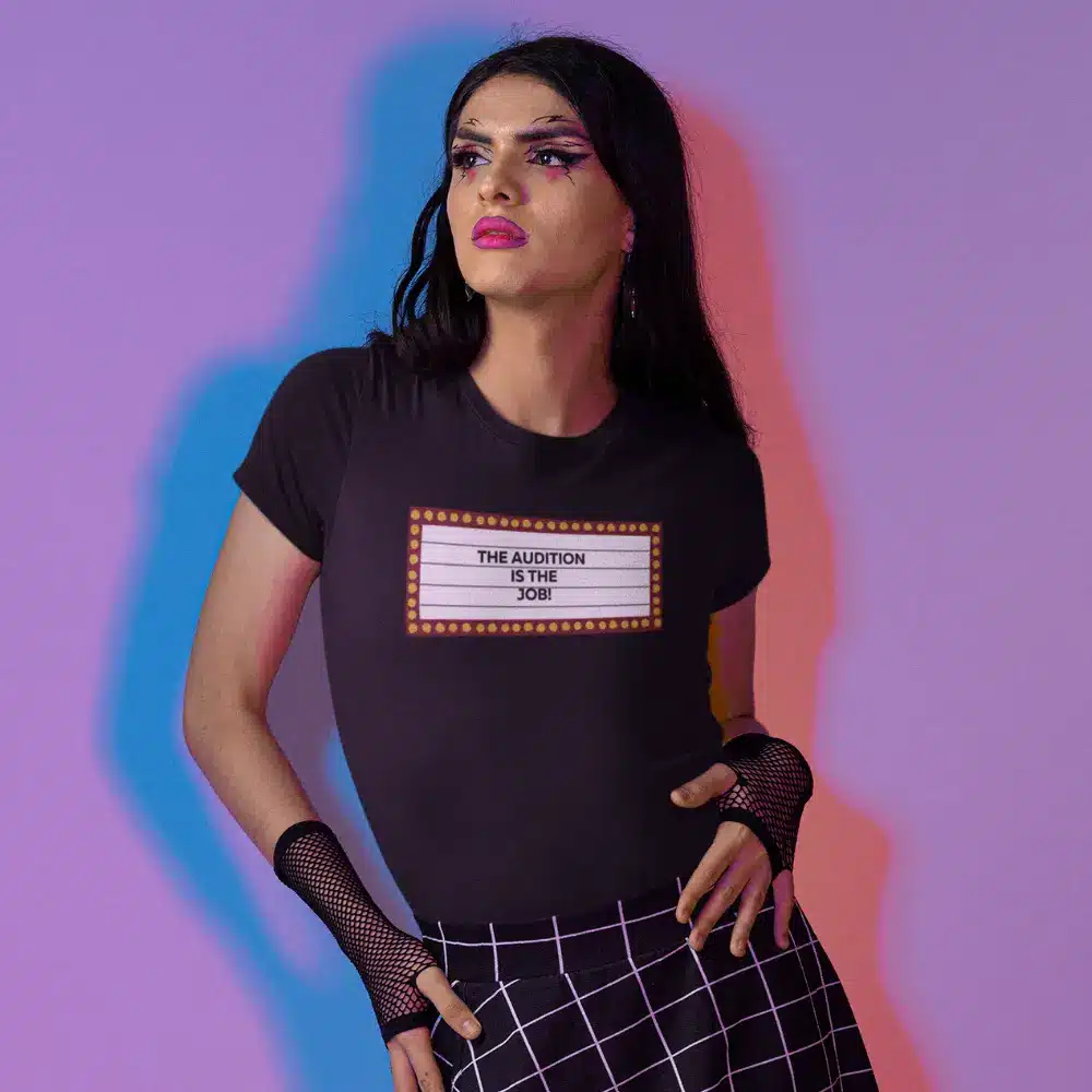 Person wearing a black t-shirt with the text "THE AUDITION IS THE JOB!" printed on it.