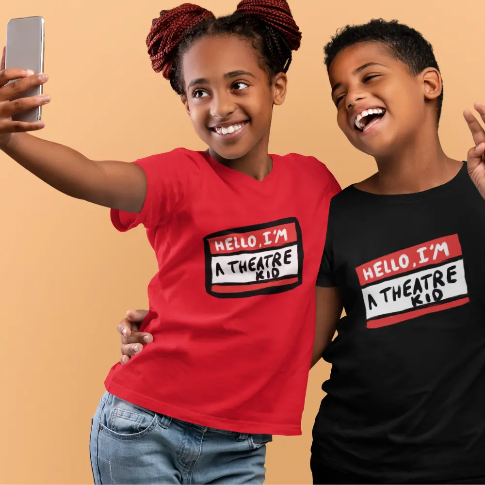 Two children wearing t-shirts with the text "Hello, I'm a Theatre Kid" printed on them, taking a selfie.