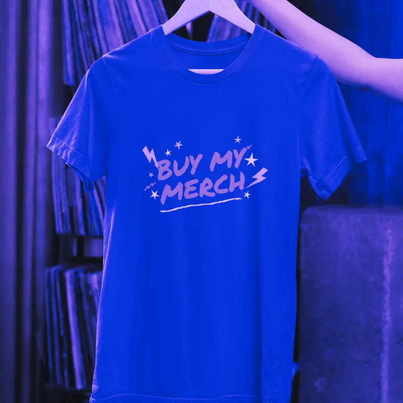 A hand holding a hanger with a t-shirt displaying "Buy My Merch"