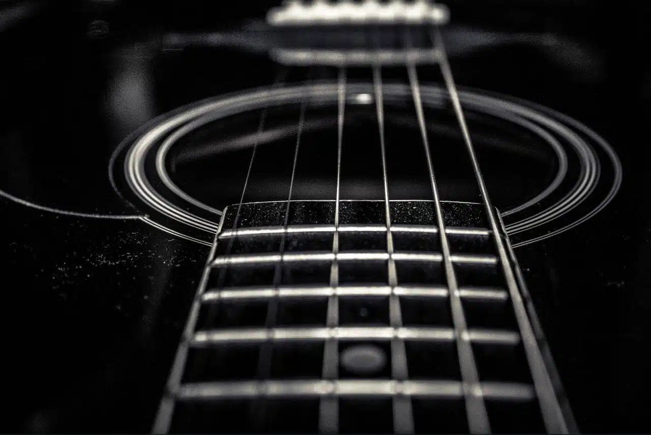 Close-up view of an acoustic guitar, focusing on the strings and sound hole with detailed, intricate lines.