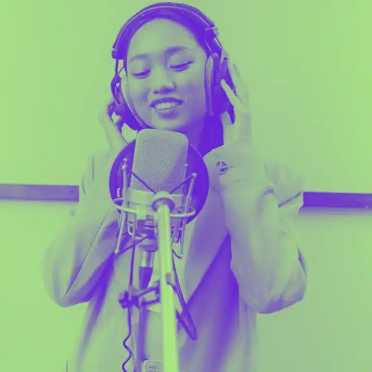 Young Asian female singer recording vocals in a studio with a microphone and headphones, expressing joy and concentration in a vibrant purple tint.