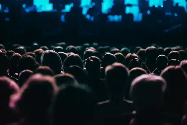 A single individual stands out in a crowded concert, viewed from behind, emphasizing the unique perspective of a seat filler at a live event, captured in a moody, dimly lit setting.