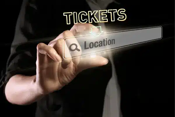 A person interacts with a futuristic holographic interface displaying the word "TICKETS" and a search bar labeled "Location", symbolizing the advanced search technology for tickets on the best seat filler website.