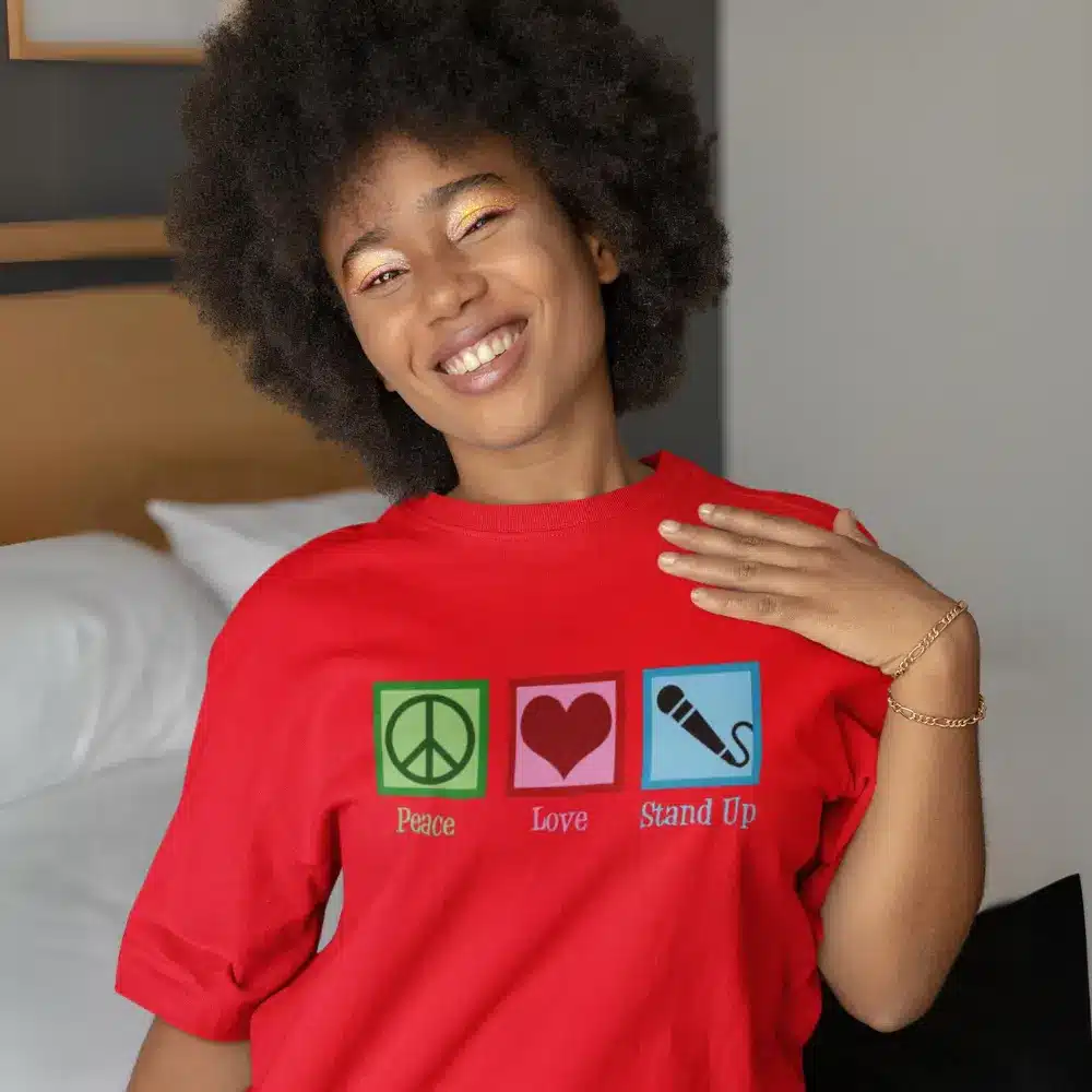 Smiling woman wearing a red t-shirt with 'Peace, Love, Stand Up' design from the OTL Spotlight curated collection
