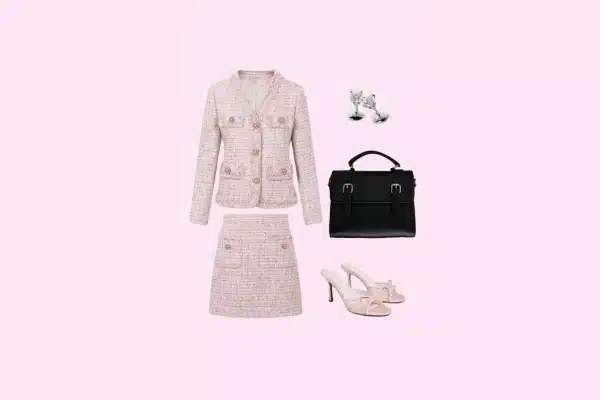 Pink tweed skirt suit with black handbag, pink heels, and silver earrings.