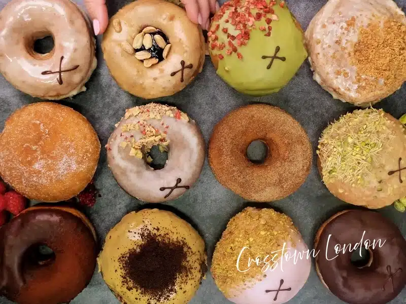 Crosstown London doughnuts in assorted glazes and toppings arranged in a grid—London food gift idea.