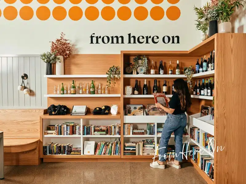 From Here On Chicago — modern market & bottle shop with shelves of wine, books, and gifts; shopper browsing.