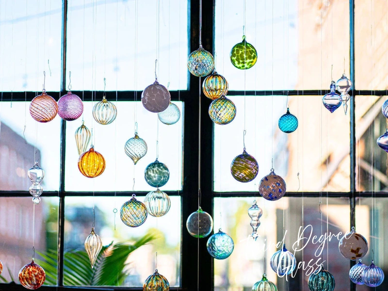 Colorful hand-blown glass ornaments hanging in a window at Third Degree Glass Factory, St. Louis artisan gift