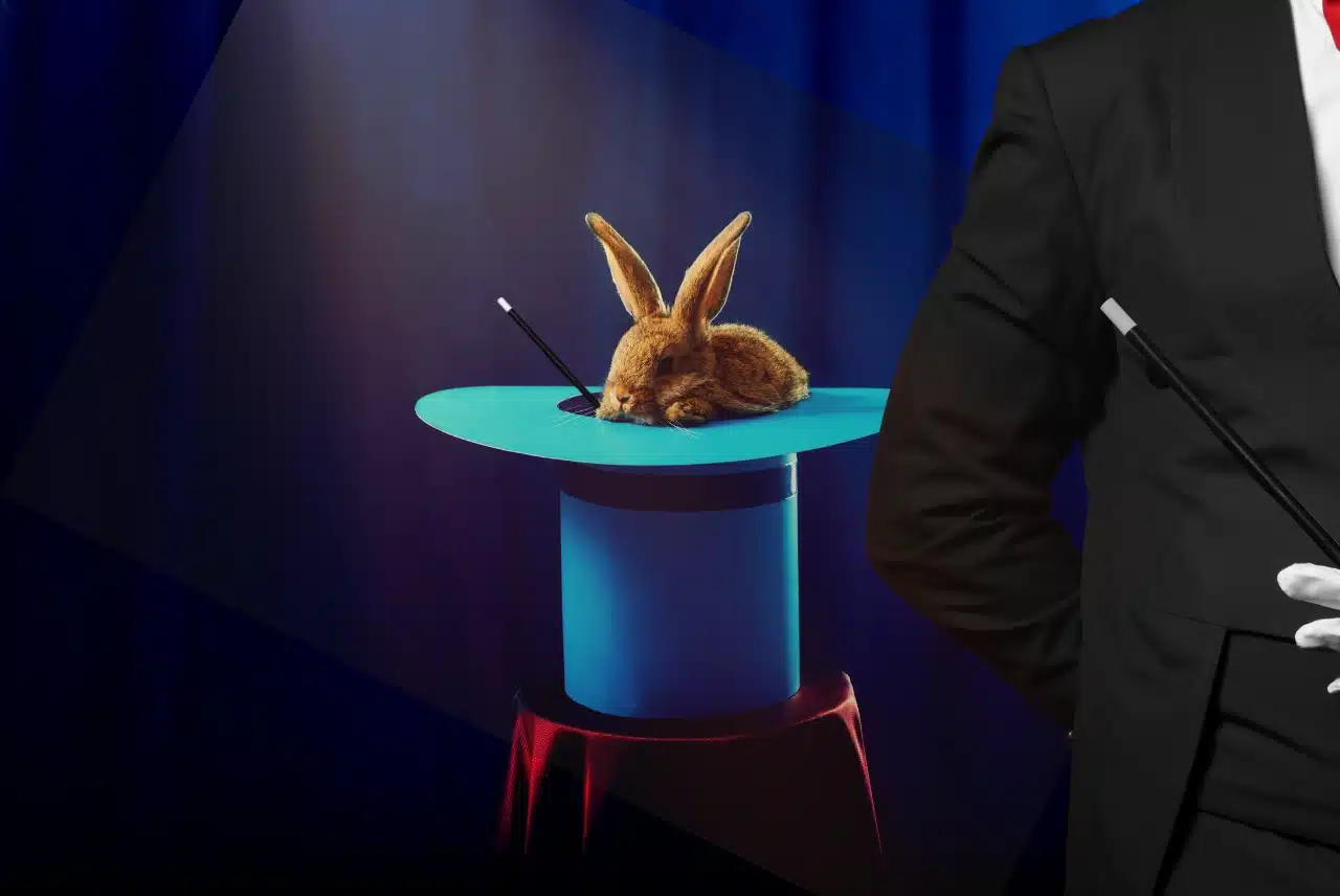 Magician performing a classic rabbit-in-the-hat magic trick on stage