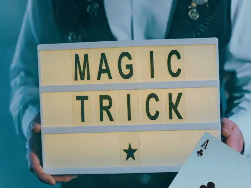 magic trick sign with playing card held by magician