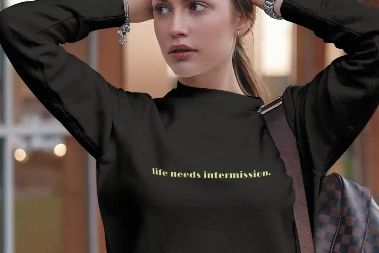 Life Needs Intermission dark crewneck sweatshirt with green text on the front.
