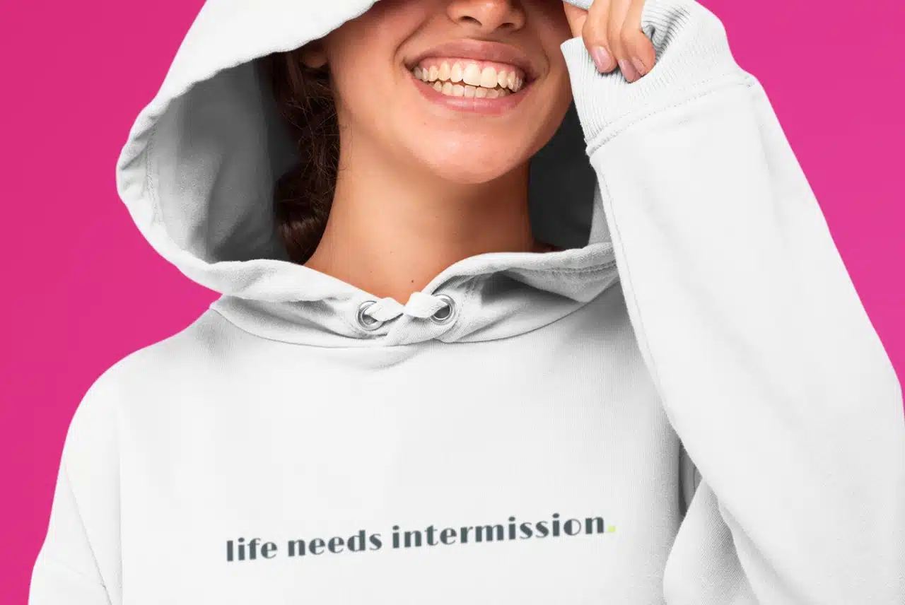 Life Needs Intermission light hoodie with black text on the front.