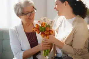 Mother receiving tulips and event tickets as a Mother’s Day experience gift while smiling with her adult daughter