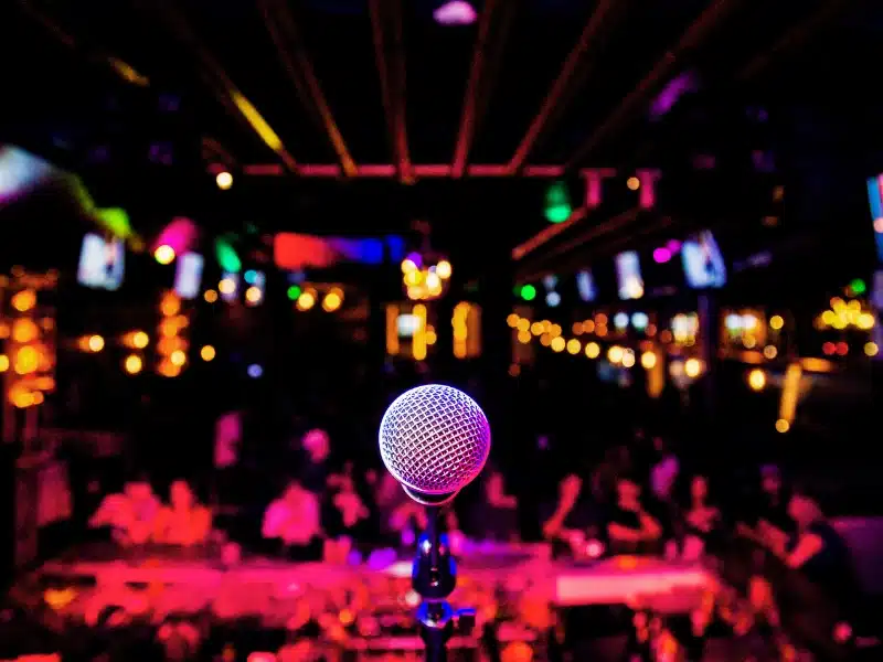 Microphone on a comedy club stage with audience seats facing forward.