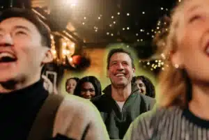 Audience laughing at a live comedy show in a warmly lit club, with smiling guests facing the stage.