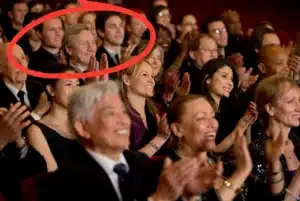 Theatre audience applauding during a live performance, with several guests seated together in the crowd.