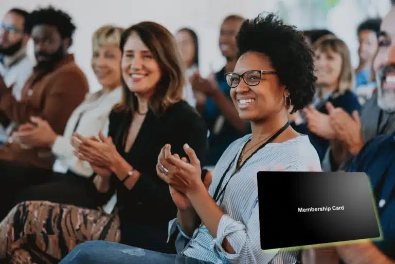 Diverse group of people applauding at an event, with a black membership card graphic in the foreground.