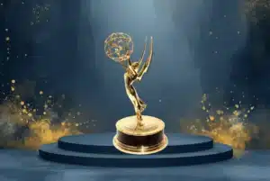 Gold Emmy-style award statue on a dark blue stage with gold confetti accents.